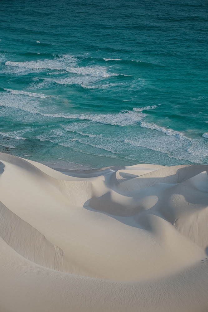 Coastline with rippled sand. Merging dunes and ocean alongside rippled sand and clear water