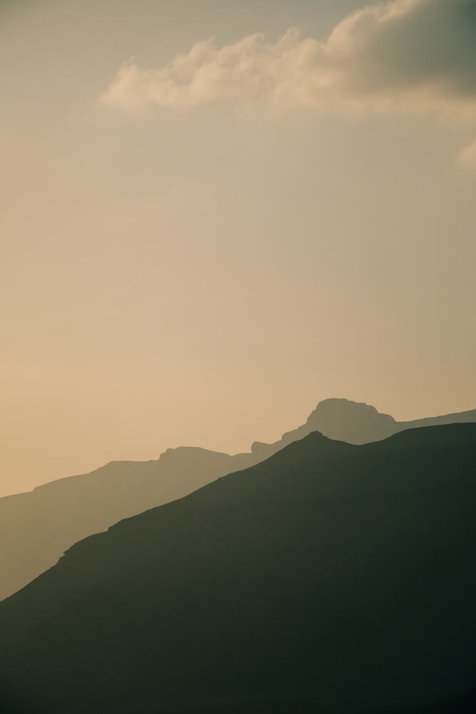 Mountain clouds shadows. Dramatic mountain profile with gentle clouds and shadow play during golden hour