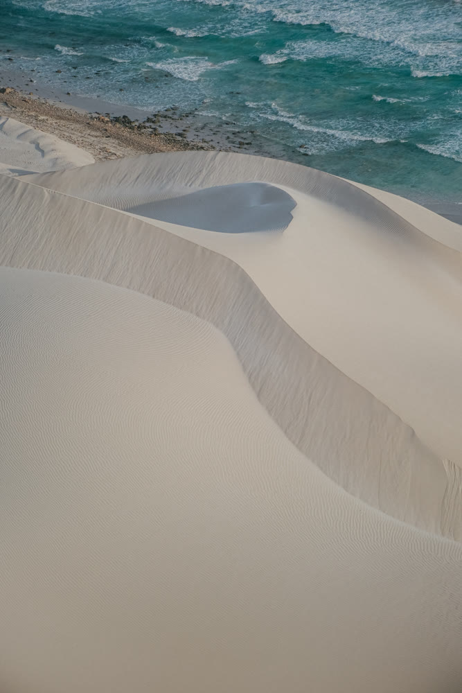 Sand meets sea. Vivid coastal scene showcasing sculpted sands and vibrant ocean hues during sunset