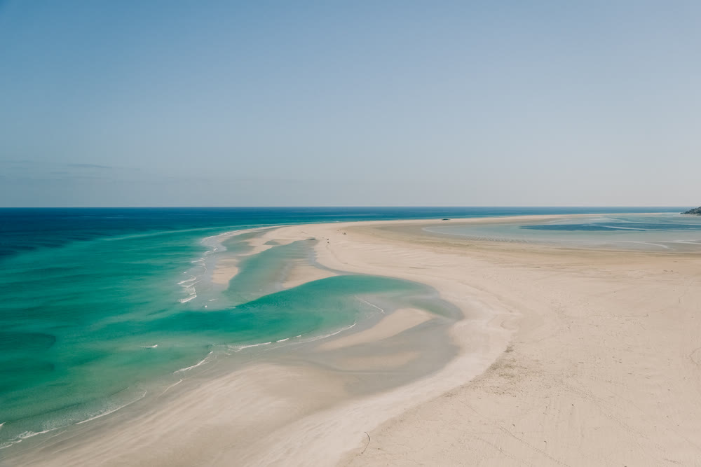 Minimalist travel visuals featuring expansive turquoise waters and sweeping shoreline curves