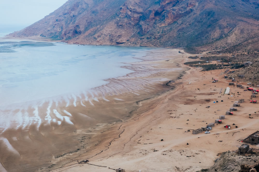 Seaside adventure scene. Coastal landscape with vehicles. Shoreline featuring vehicles and rugged mountains