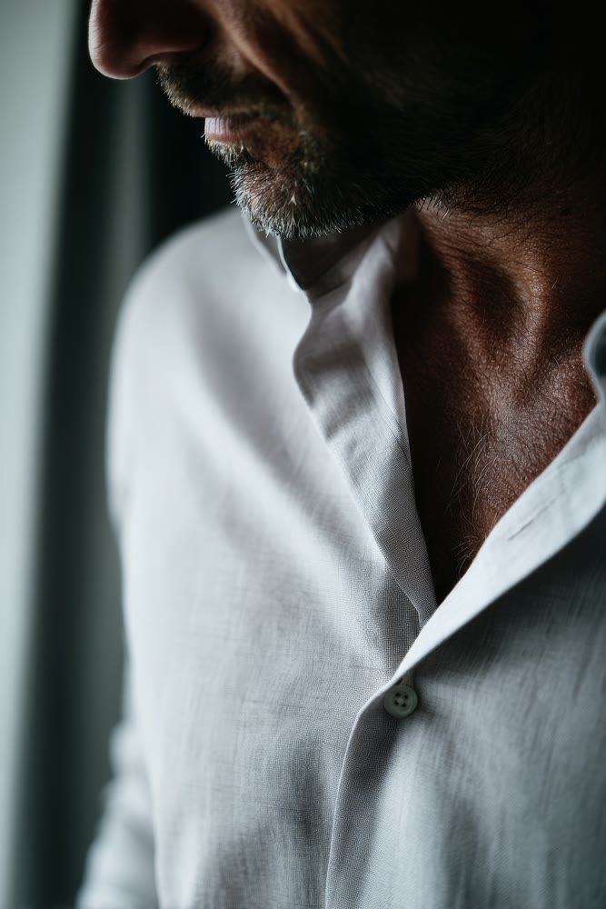 Intimate depiction of businessman contemplating with textured fabric and subdued shadows emphasizing elegance